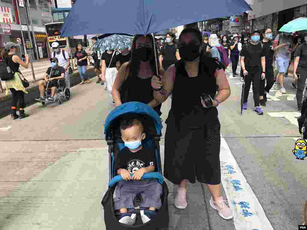 有家长带同年幼儿子一同戴上口罩参与10月5日”全民蒙面游行”,反对当局实施”禁蒙面法” (美国之音汤惠芸拍摄)