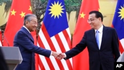 马来西亚总理马哈蒂尔和中国总理李克强在人民大会堂举行记者会后握手。(2018年8月20日)