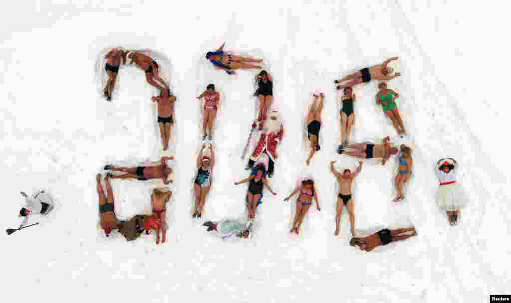 在俄罗斯西伯利亚城市克拉斯诺亚尔斯克的叶尼塞河河岸上,冬眠游泳俱乐部的成员们躺在雪地上组成了“2018”,迎接新年和圣诞节。他们多数人穿着泳装,也有人装扮成俄罗斯圣诞老人和白雪少女(2017年12月24日)。