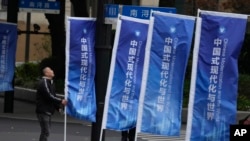 资料照:一名工人在上海街头整理竖起的宣传旗帜:“中国式现代化与世界”。 (2023年4月21日)