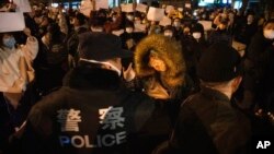 2022年11月27日,警察在北京街头和手举白纸的抗议者对峙。