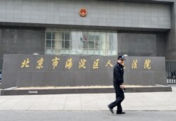 一名警察走过正在审理中国反腐败活动人士丁家喜的北京市海淀区人民法院。(2014年4月8日)