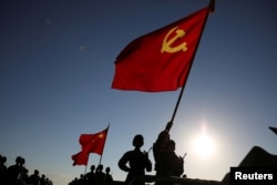 中国解放军军人在内蒙古朱日和训练基地准备参加阅兵,庆祝解放军建军90周年。中共党旗在前,国旗居中,军旗在后(2017年7月30日)