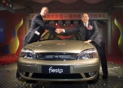 资料照:中国兵器工业集团董事长尹家绪(右)在时任长安汽车高管时与福特公司付执行官瑟斯菲尔德握手。