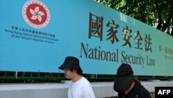 资料照:行人走过香港街头港版国安法的宣传牌。(2020年7月15日)