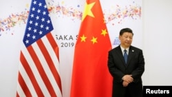 资料照:中国国家主席习近平在日本出席G20峰会期间在美中国旗前等候美国总统特朗普前去参加双边会谈。(2019年6月29日))