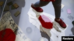 资料照:在北京的中国人民抗日战争博物馆内,一名参观者走在玻璃地板下展示的二战期间缴获的日本旗帜。(2015年9月1日)