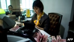 2018年8月8日在上海的一家银行,员工使用点钞机点算100元(相当于14.6美元)的钞票。