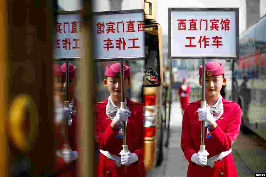 中共19大第二天上午会议结束,代表们回宾馆,服务员举牌展示宾馆车辆(2017年10月19日)。