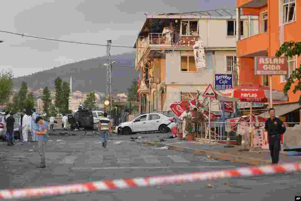 Turkish police officers work near the site of an explosion at a police station, seen right, in Istanbul's Sultanbeyli neighborhood, early Monday, Aug. 10, 2015.