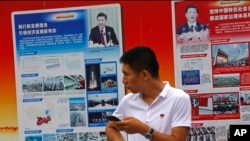 2018年8月22日,北京地铁站外的政府宣传广告牌宣传中国国家主席习近平和中国的经济成就,一名男子站在旁边。