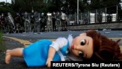 资料照:在香港民众反送中游行期间防暴警察堵住一个路口,路口躺着一个玩具娃娃。