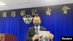 台湾国防部官员2023年6月13日展示最新版民防手册。(路透社)