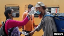 印度一名卫生工作者在孟买一个列车站为旅客量体温(路透社2021年4月7日)