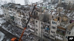 2023年2月15日救援人员在乌克兰波克罗夫斯克清理被俄罗斯火箭摧毁的住宅楼废墟,专家警告说,这场已造成双方数万人死亡、许多城市化为废墟的战争可能会持续多年。 (美联社照片)