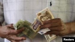 一位顾客在北京的一家银行数钱(资料照片)