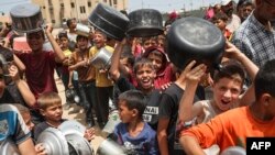 资料照片:被驱离的巴勒斯坦儿童在加沙拉法城排队领取食物。(2024年5月19日)