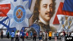 Tourists visit Dvortsovaya Square in front of a giant banner depicting Peter the Great, the founder of Saint Petersburg, in central Saint Petersburg on June 9, 2024.