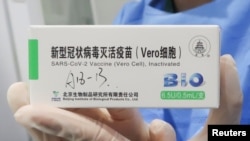 在中国政府组织的访问期间,一名护士在北京的疫苗接种中心拿着一盒北京生物制品研究所生产的冠状病毒病 (COVID-19) 疫苗。(2021年4月15日)