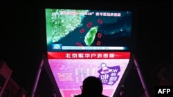 北京一家购物中心外的大荧幕上,一名男子正在观看有关中国围绕台湾进行军事演习的新闻节目。(法新社:2024年10月14日)