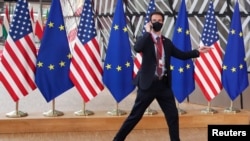 资料照:布鲁塞尔欧盟总部内,一名安保人员从美国和欧盟旗帜前走过。(2021年6月15日)