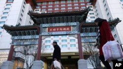 资料照片:居民从北京王府半岛酒店门前经过。(2018年11月16日)