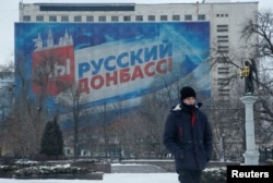 在亲俄反政府武装控制的顿涅茨克市,一名行人走过展示“我们是俄罗斯的顿巴斯”标语的宣传横幅。(2022年1月24日)