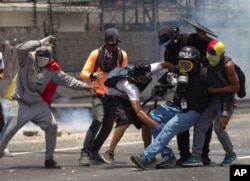 2017年4月10日，委内瑞拉加拉加斯，示威者与国民警卫队冲突时，帮助一名腿部受伤的记者