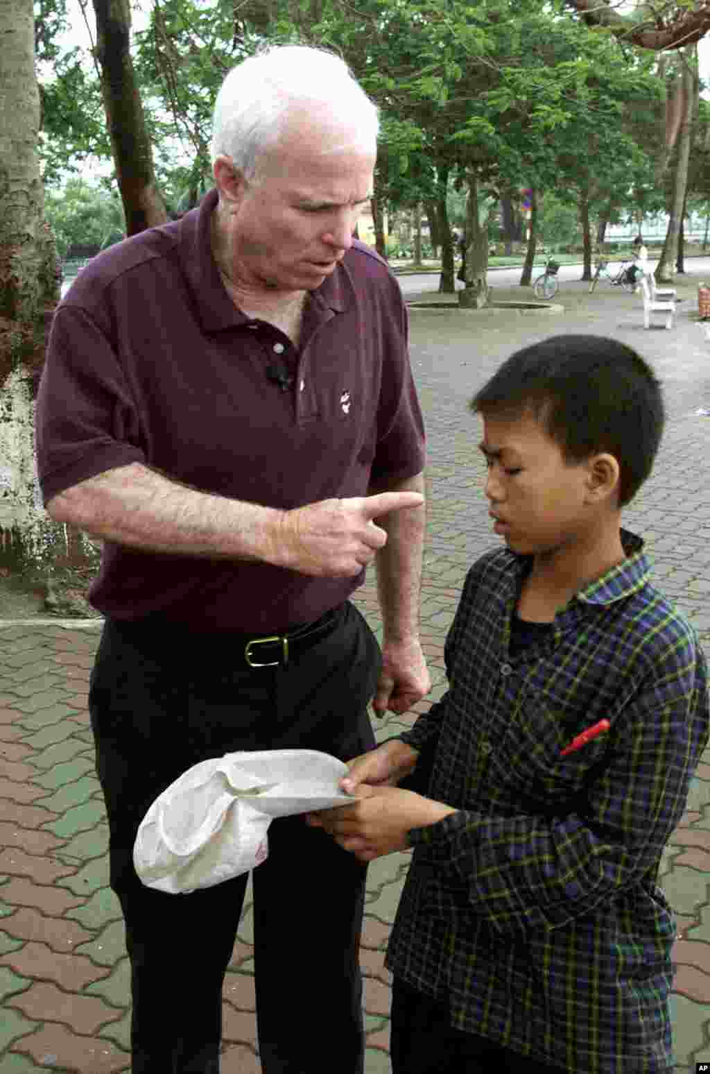 Ông McCain la mắng một cậu bé xin tiền bên bờ Hồ Trúc Bạch ở Hà Nội, ngày 27 tháng 4 năm 2000. Theo tường thuật của AP, trước đó ông đã cho tiền nhưng rồi ông nổi nóng và đuổi đi chỗ khác sau khi cậu bé tới hỏi xin lần nữa.  