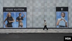 在中国湖北省武汉市,一名男子带着口罩走过法国奢饰品牌路易威登(Louis Vuitton)的一家门店。(2020年2月25日)