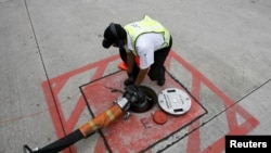 资料照:新加坡樟宜机场的一名技工将一条飞机加油管与停机坪下的储油罐出口连接起来。