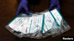 一名药房工作人员在展示KN95防护口罩。(2020年4月16日)