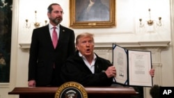 美国卫生与公共服务部长阿扎尔在旁边看着特朗普总统展示刚签署的对抗新冠病毒的开支法案(2020年3月6日)。