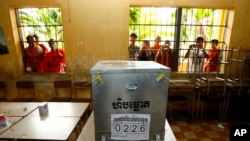 柬埔寨上届大选期间,一些年轻人在首都金边一处投票站对着投票箱拍照(2013年7月28日)
