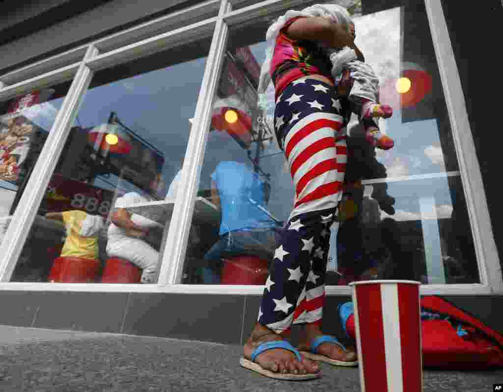 A woman, wearing a Stars and Stripes-designed pants, cuddles her baby outside an American fast food chain on Nov. 8, 2016 in Manila, Philippines.