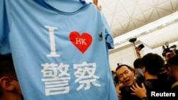 2019年8月13日在香港国际机场抗议的示威者从身穿黑色T恤衫的环球网记者付国豪(中)的背包里找出一件印有“我爱香港警察”图样的T恤衫。