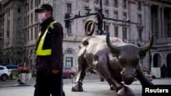 资料照:一名戴着口罩的保安走过上海外滩金融牛旁。