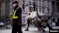 资料照:一名戴着口罩的保安走过上海外滩金融牛旁。