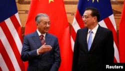 马来西亚总理马哈蒂尔(左)与中国总理李克强在北京人大会堂的签约仪式上。(2018年8月20日)