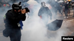 一名头戴标有“媒体”字样头盔,前胸挂记者证的摄影记者在催泪弹的烟雾中拍摄香港的反送中抗议。(2019年10月6日)