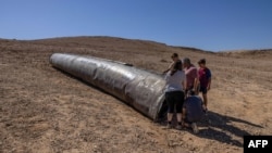 Люди оглядають залишки іранської ракети, яка впала на Ізраїль, 3 жовтня 2024 року. Фото: MENAHEM KAHANA/AFP