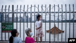 中国武汉居民注视着将要淹没长江岸边亭子顶部的洪水。(2020年7月12日)