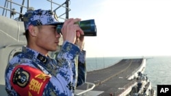 2013年11月26日,中国海军“辽宁号”航空母舰在南中国海试航期间,一名执勤水兵在甲板上了望。