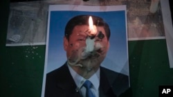 2020年6月4日,星期四,在香港铜锣湾维多利亚公园为1989年天安门广场大屠杀遇难者举行的守夜仪式上,中国国家主席习近平的照片上燃烧着一支蜡烛。