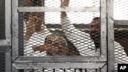 Mohammed Badie, bottom center, and senior Brotherhood figure Salah Soltan, right, gesture during an appearance at a courtroom in Cairo, Egypt, April 1, 2014.