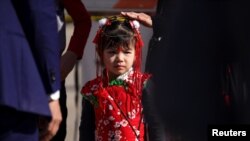 在加州蒙市枪击现场,一名身着节日盛装的亚裔女孩看着执法者在忙碌。(2023年1月22日)