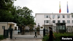 资料照片:2022年8月8日,一名男子走过缅甸驻北京大使馆外站岗的武警士兵。(路透社照片)