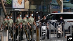 在美国驻北京大使馆外守卫的保安看一队武警走过。(2022年8月3日)