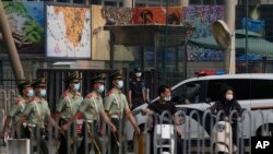 资料照片: 在美国驻北京大使馆外守卫的保安看一队武警走过。(2022年8月3日)