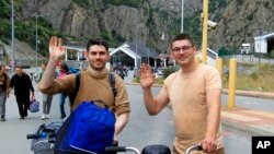 FILE - Two Russians wave toward a photographer after they crossed the border between Georgia and Russia at Verkhny Lars in Georgia, Sept. 28, 2022.